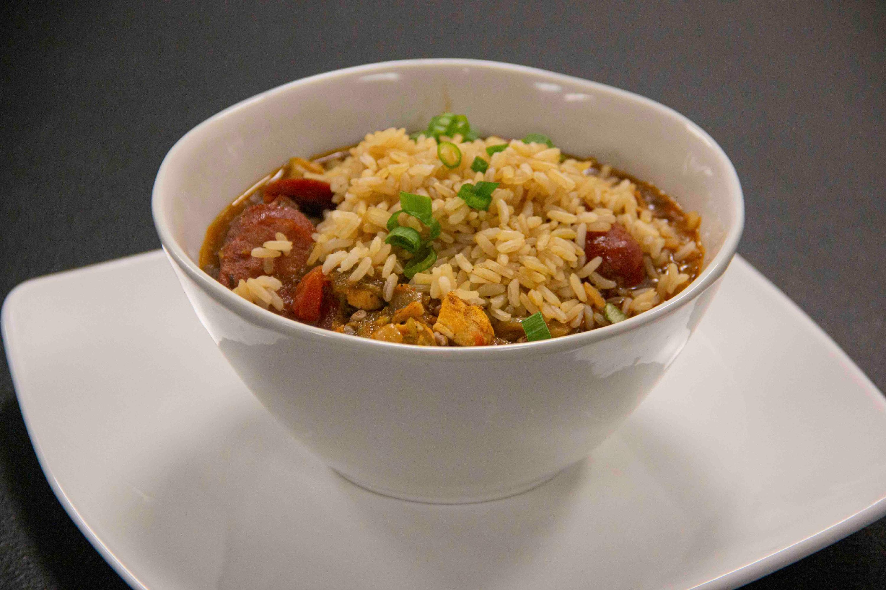 A bowl of gumbo rests on a dark table